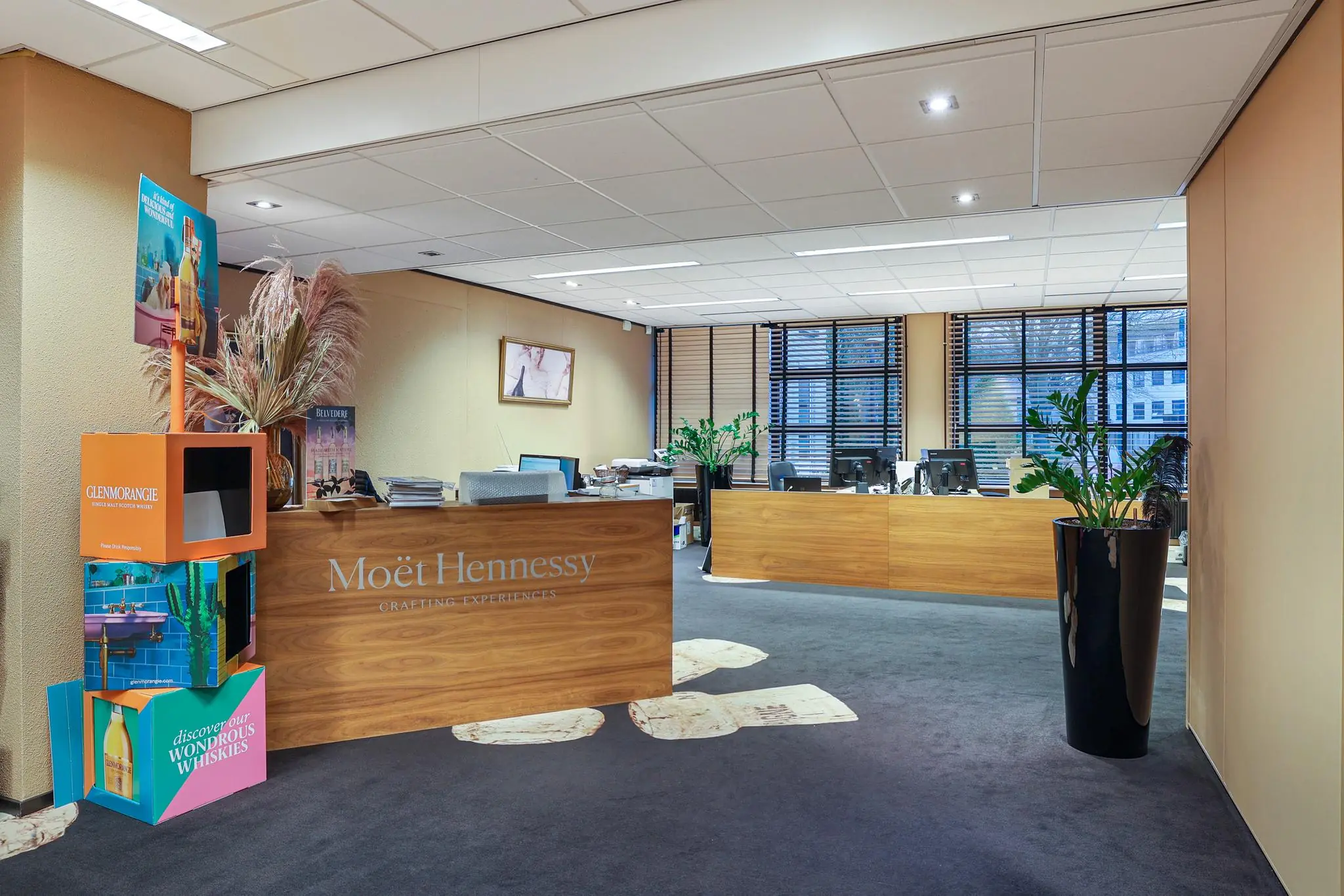 Moderne kantoorruimte aan de Oude Utrechtseweg met een houten receptiebalie van Moët Hennessy en kleurrijke display van Glenmorangie whisky.